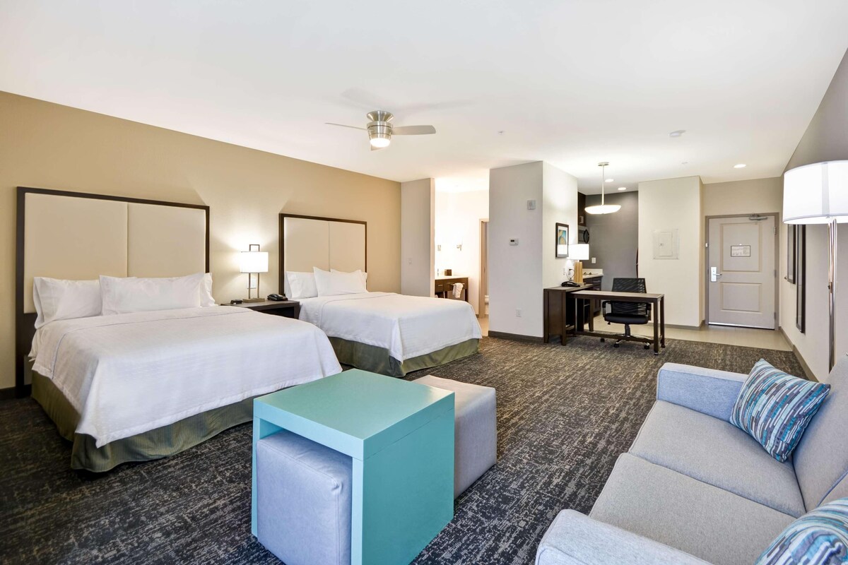 Una habitación de hotel con dos camas, un escritorio, un sofá y una pequeña mesa.
