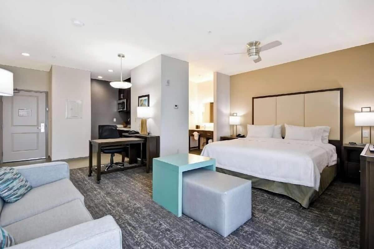 Une chambre d’hôtel équipée d’un lit, d’un bureau, d’une chaise, d’un canapé et d’un ventilateur de plafond.