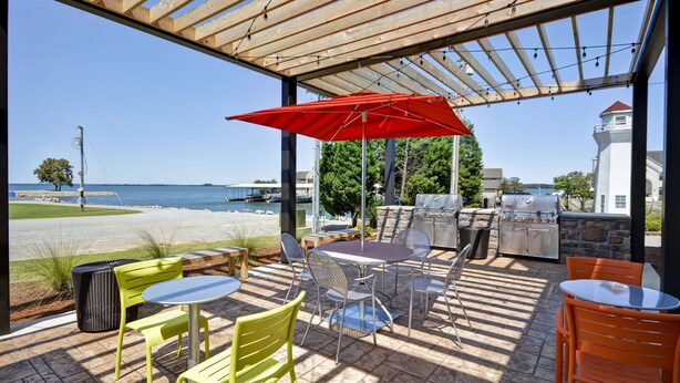 An outdoor patio with a view of the sea, a grill, and seating areas. - Home2 Suites by Hilton Decatur Ingalls Harbor (Decatur)