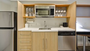 A compact kitchen with a stainless steel refrigerator, a microwave, and a dishwasher. - Home2 Suites by Hilton Decatur Ingalls Harbor (Decatur)