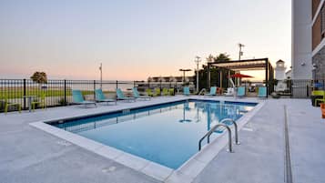 Una piscina al aire libre, sillones reclinables de piscina