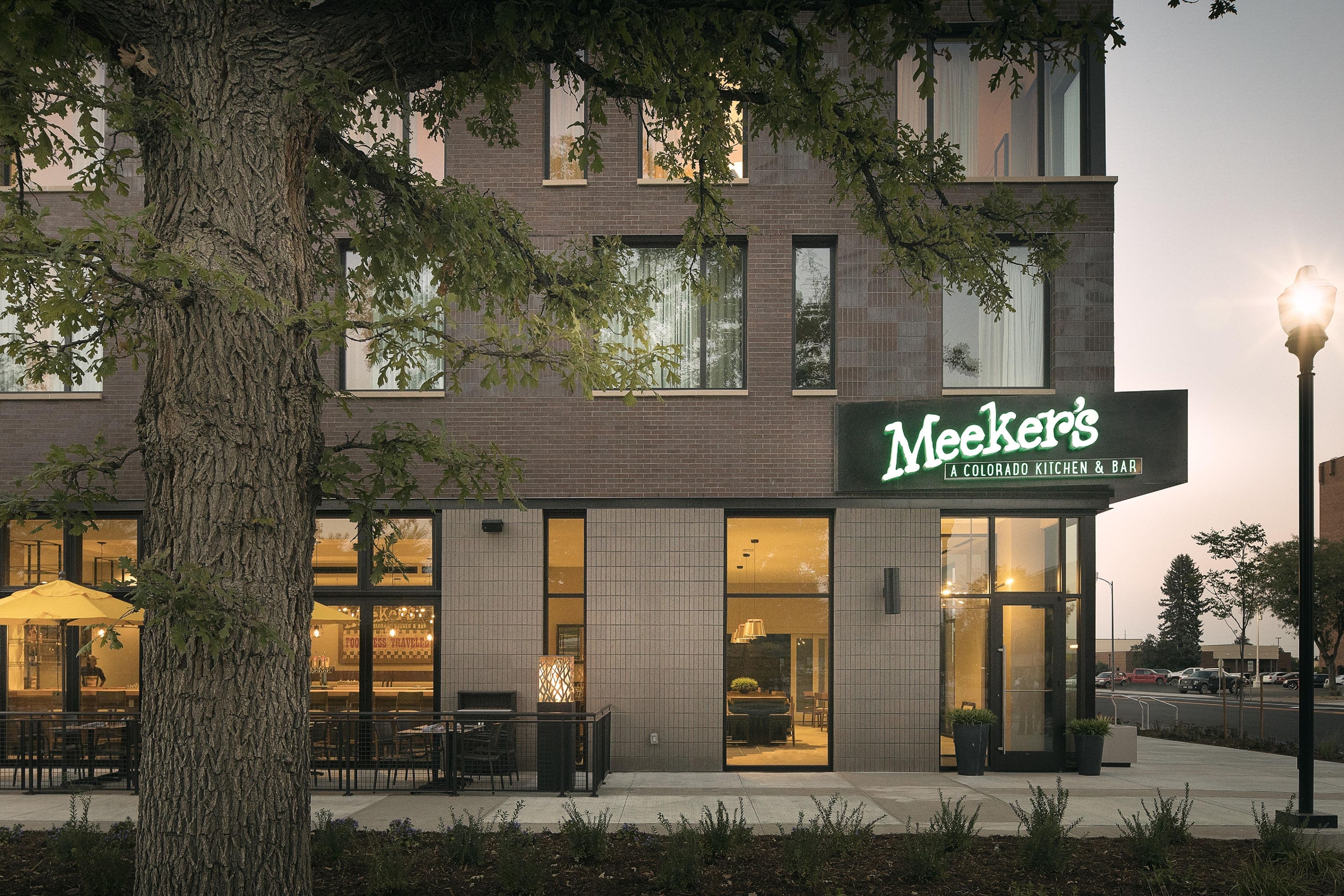A building with a sign reading 'Meeker's Colorado Kitchen & Bar' and a visible outdoor seating area with tables and chairs.