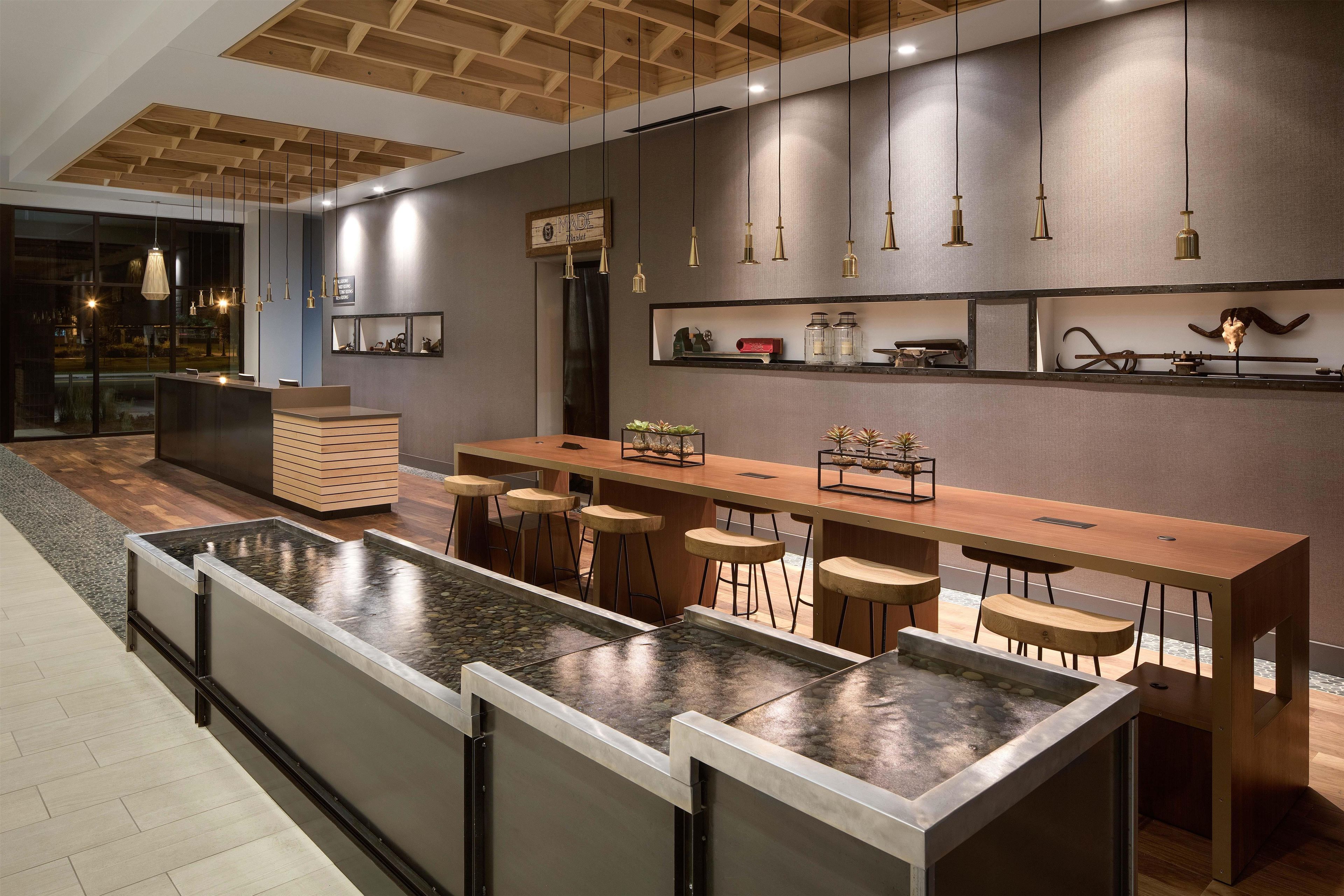 A modern bar area with a long counter, stools, and a decorative wall with shelves.