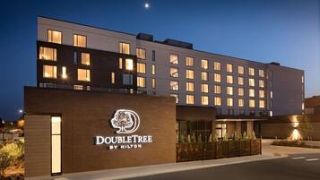 Un hôtel moderne, reconnaissable à son grand panneau « DoubleTree by Hilton », avec de nombreux étages et une entrée bien éclairée.
