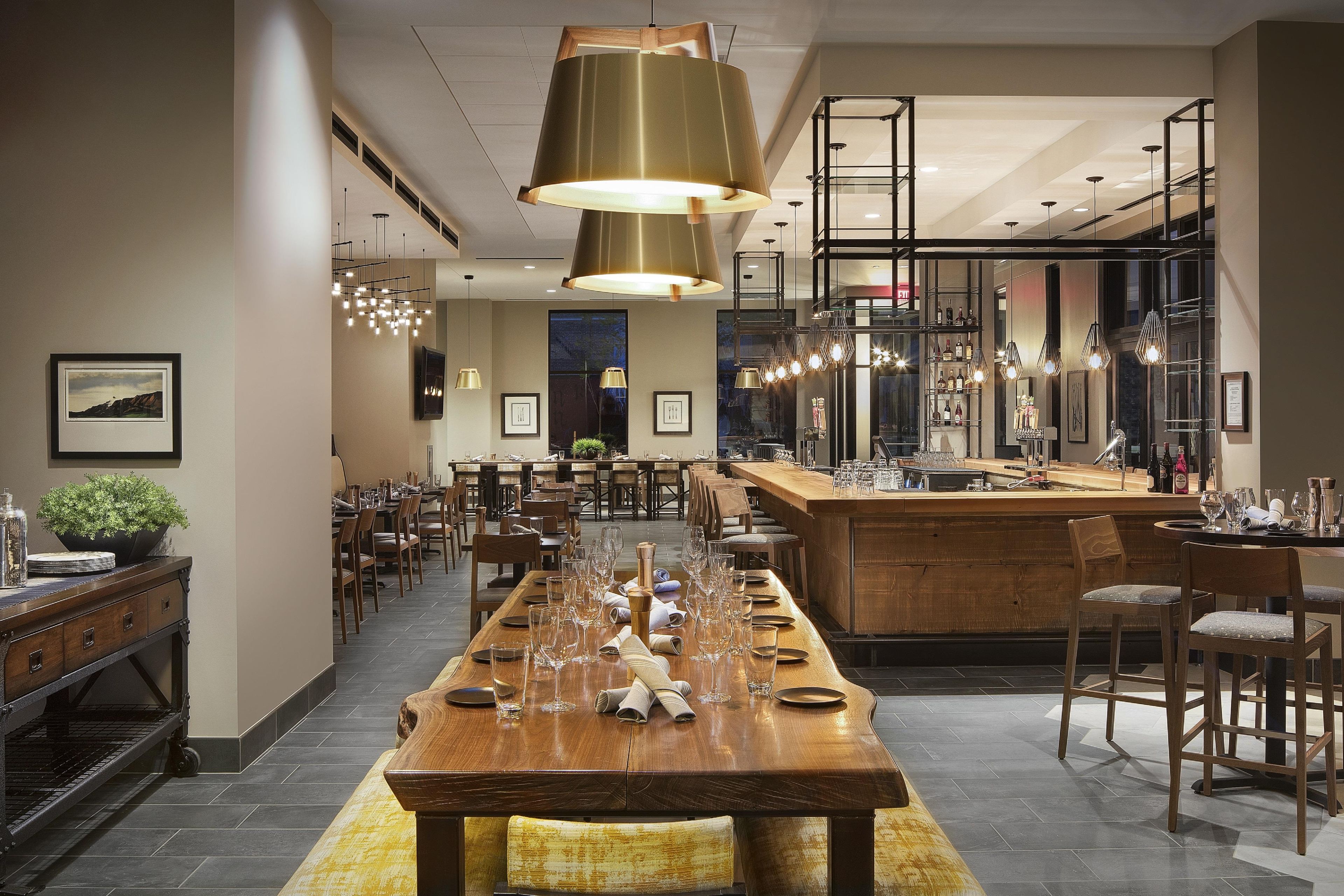 A spacious dining area with a long wooden table set for a meal, surrounded by chairs.