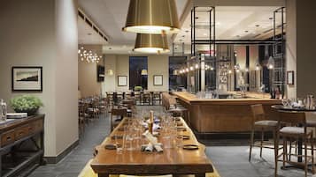 A spacious dining area with a long wooden table set for a meal, surrounded by chairs.