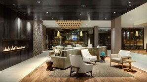A modern lobby with a fireplace, seating area, and large windows. - DoubleTree by Hilton Greeley at Lincoln Park (Greeley)