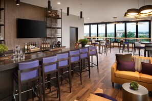 A modern bar area with high stools, a flat-screen TV, and a view of the city through large windows. - DoubleTree by Hilton Greeley at Lincoln Park (Greeley)