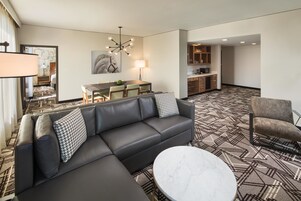 Una sala de estar moderna con un sofá modular, una mesa de centro redonda y un comedor con mesa y sillas.