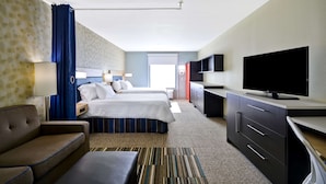 Habitación de hotel con cama, sofá, televisión, escritorio y baño.