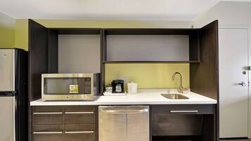 A compact kitchen with a microwave, coffee maker, and a sink.