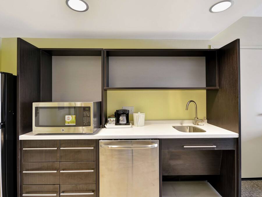 A compact kitchen with a microwave, coffee maker, and a sink.