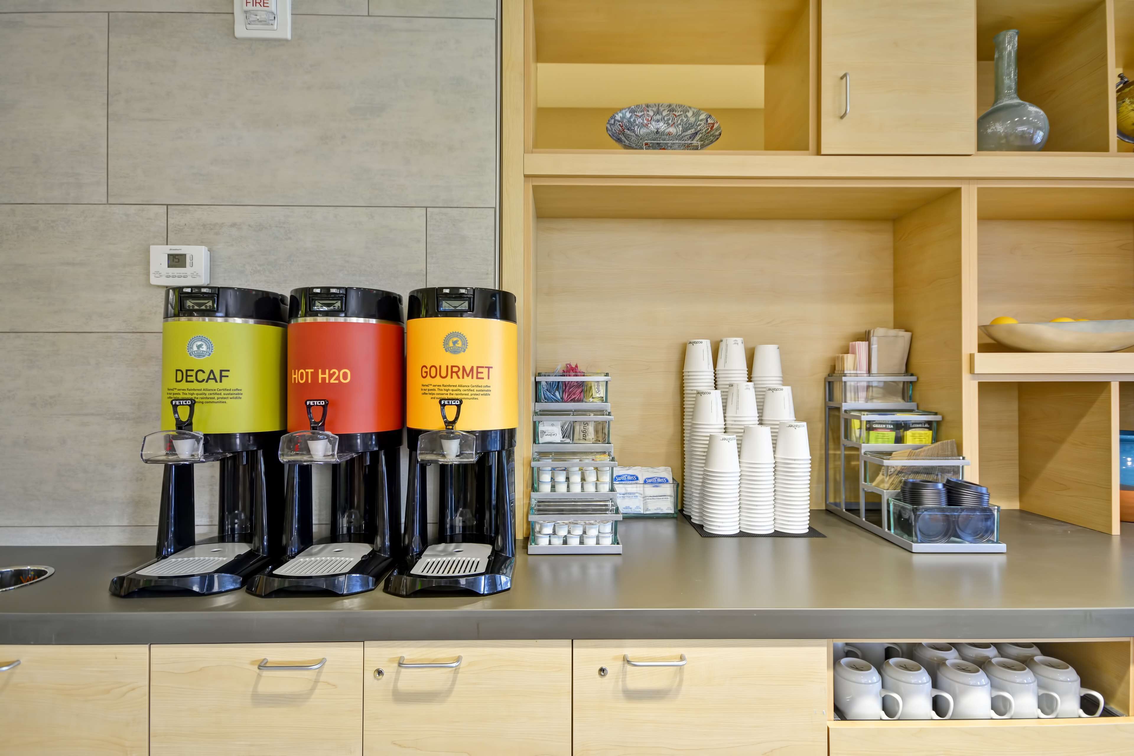 A coffee station with three beverage dispensers labeled DECAF, HOT H2O, and GOURMET.