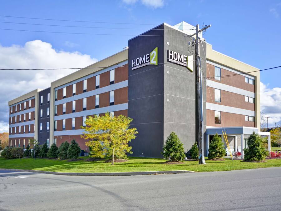 A multi-story hotel with a prominent "Home 2" sign, featuring a modern architectural design with a mix of brick and concrete facades.