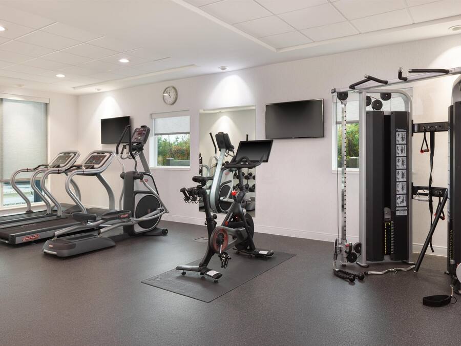 Un gimnasio con cintas de correr, elípticas y máquinas de pesas.