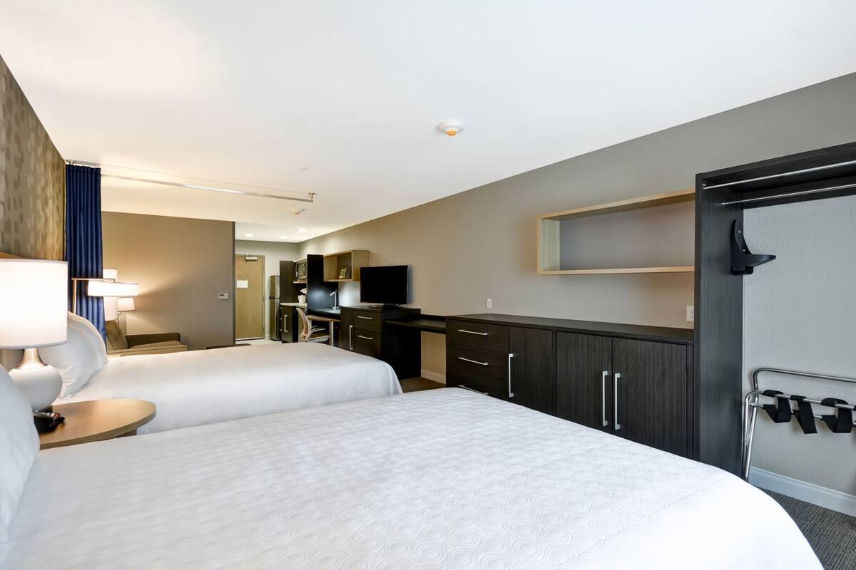 A hotel room with two beds, a desk, a TV, and a wardrobe.