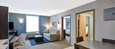 Una habitación de hotel moderna con escritorio, silla, sofá y una mesa de comedor.