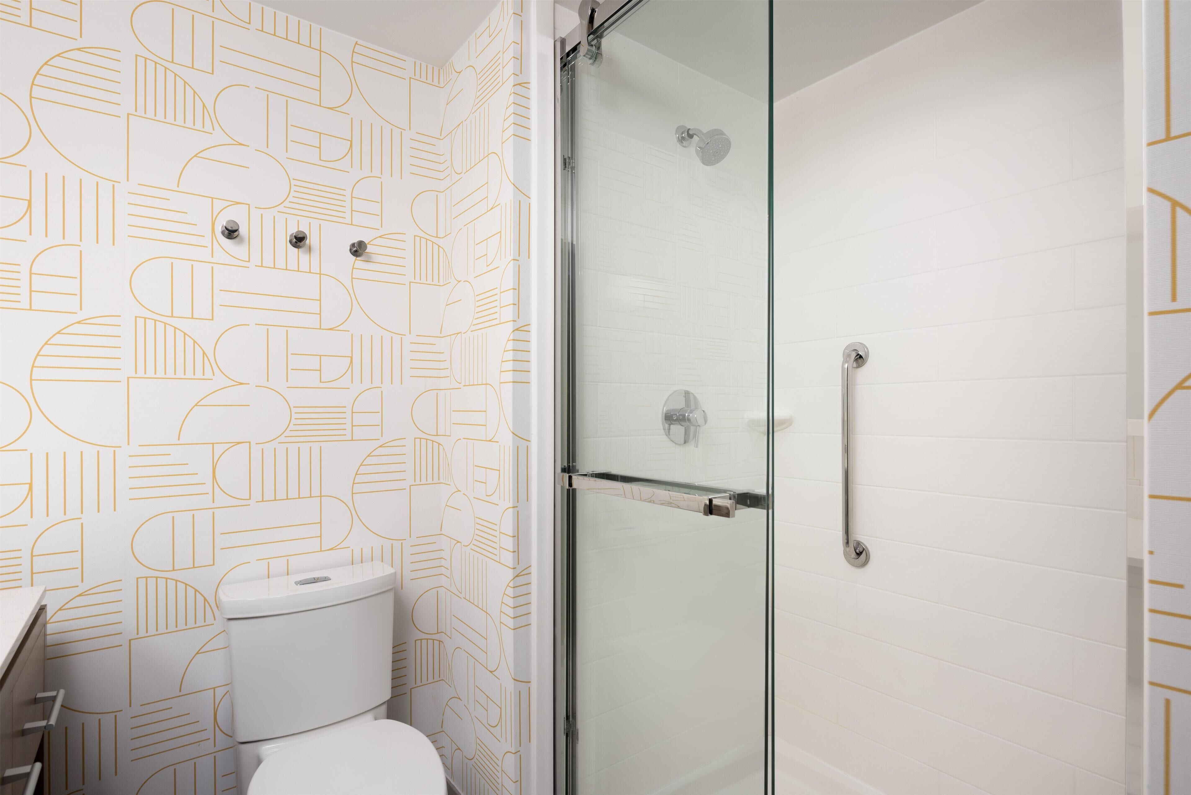 Ein Badezimmer mit Wandmuster, Toilette und einer Duschkabine.