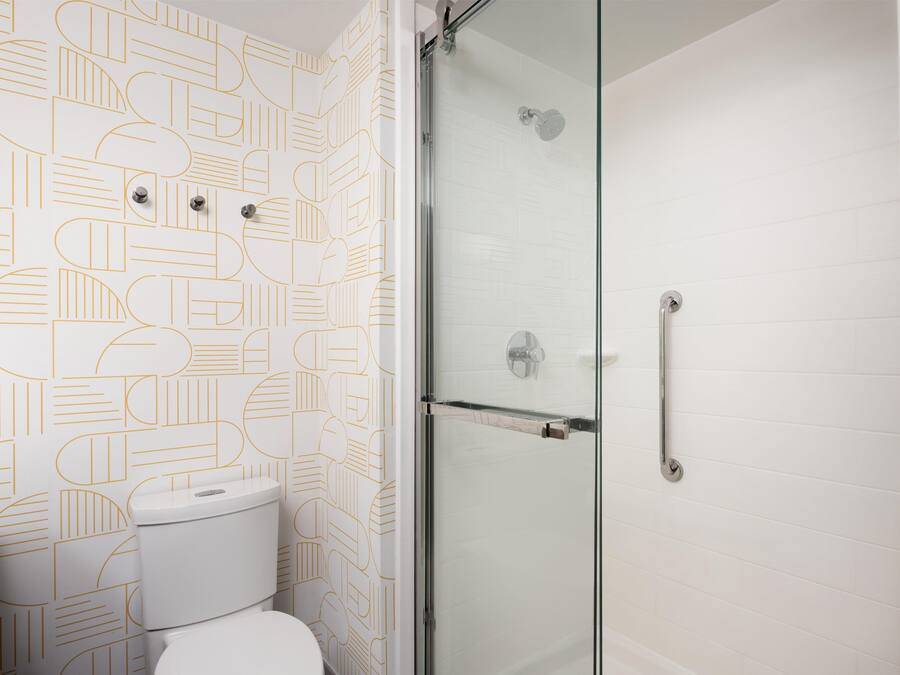 Ein Badezimmer mit Wandmuster, Toilette und einer Duschkabine.