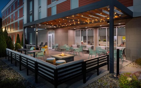 An outdoor patio area with seating, a fire pit, and string lights.