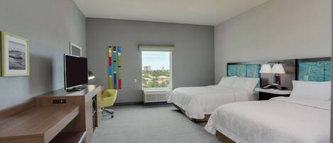 A hotel room with two beds, a desk, a TV, a chair, and a window with a view.