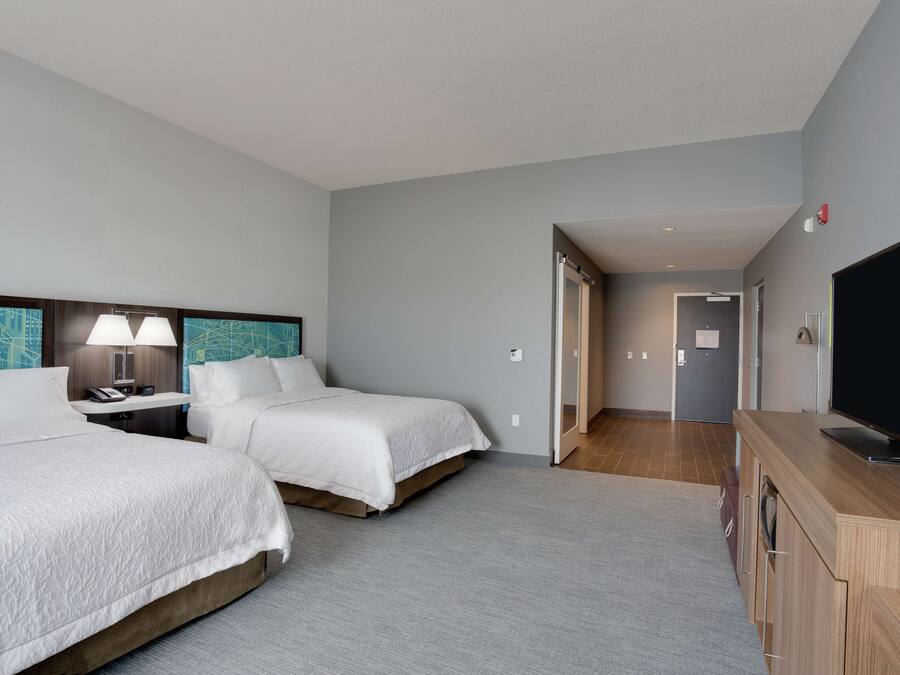 A hotel room with two beds, a TV, a desk, and a wardrobe.