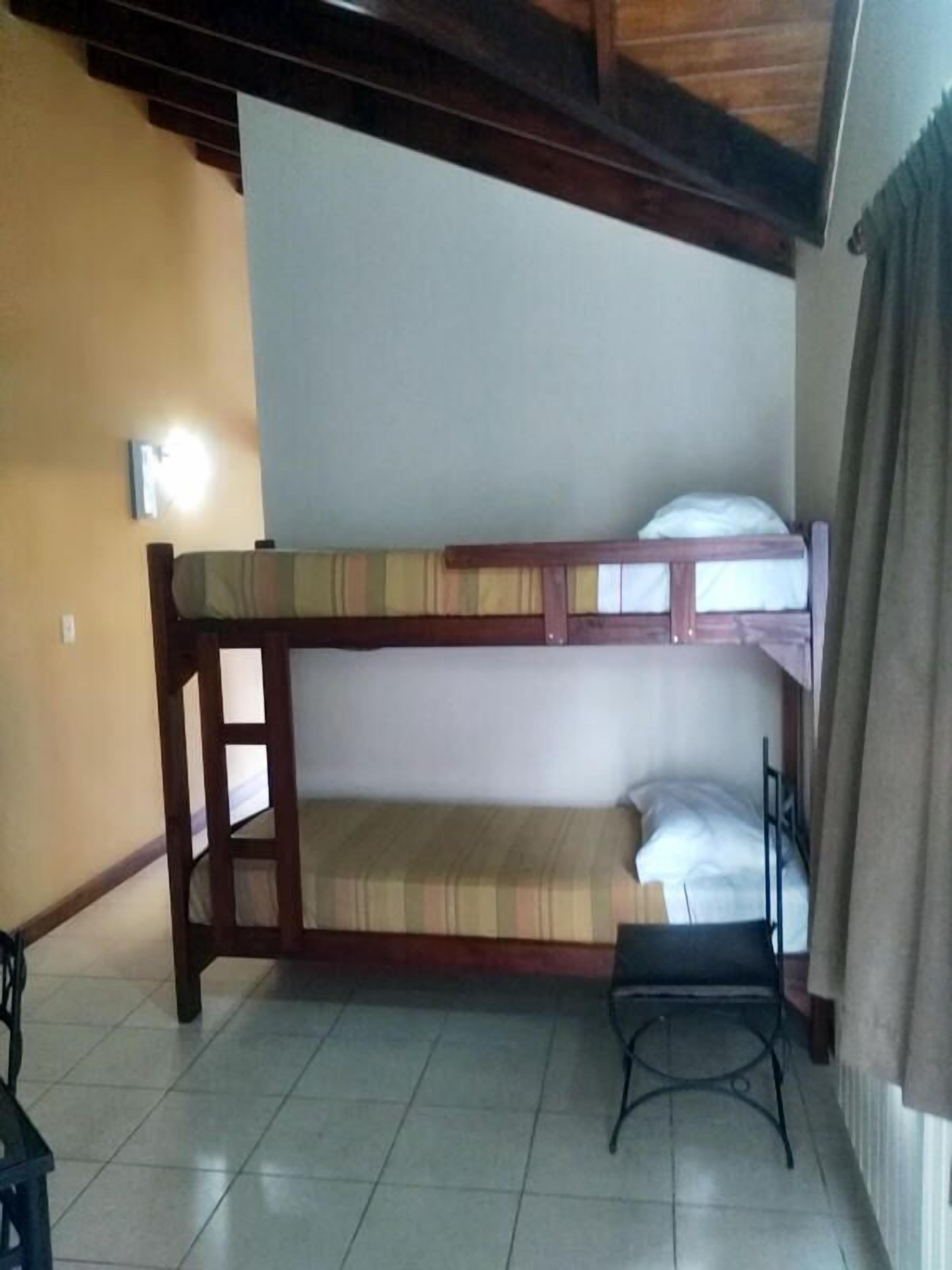 A bunk bed room with a small table and a wall-mounted light.