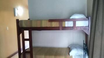 A bunk bed room with a small table and a wall-mounted light.