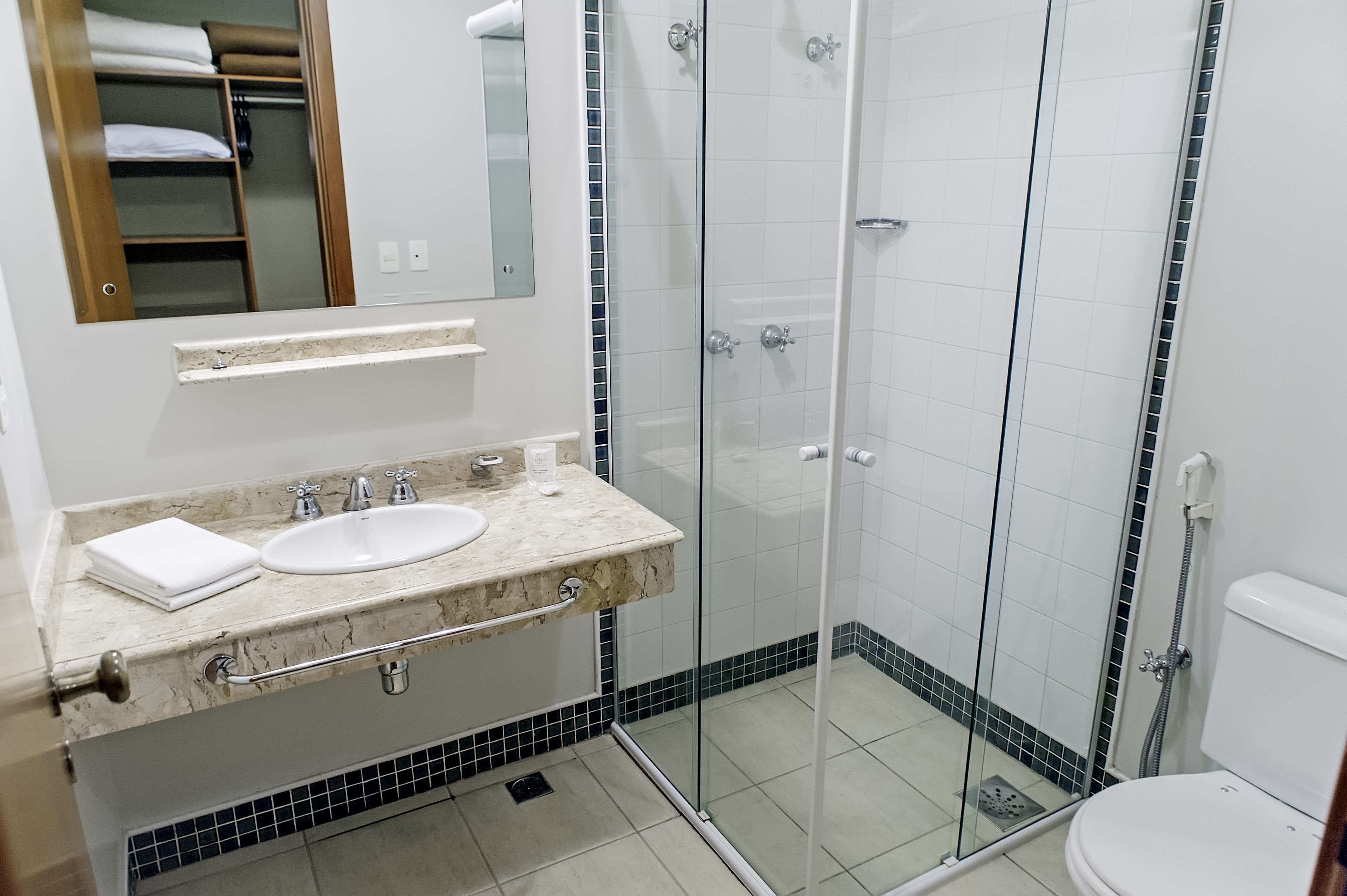 A bathroom with a glass-enclosed shower, a sink with a marble countertop, and a toilet.