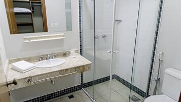 A bathroom with a glass-enclosed shower, a sink with a marble countertop, and a toilet.
