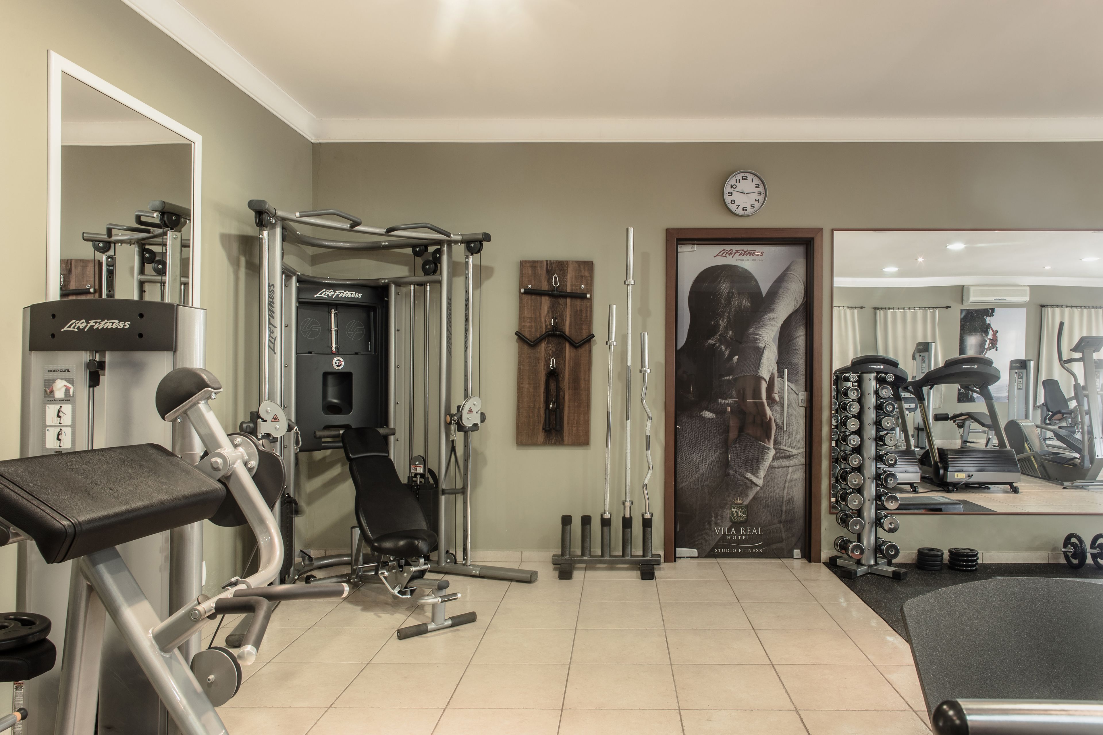A home gym with a variety of exercise equipment, including a bench press, a squat rack, and a treadmill.