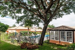 A house with a swimming pool, surrounded by greenery and a large tree. - Vila Real Hotel (Jau)