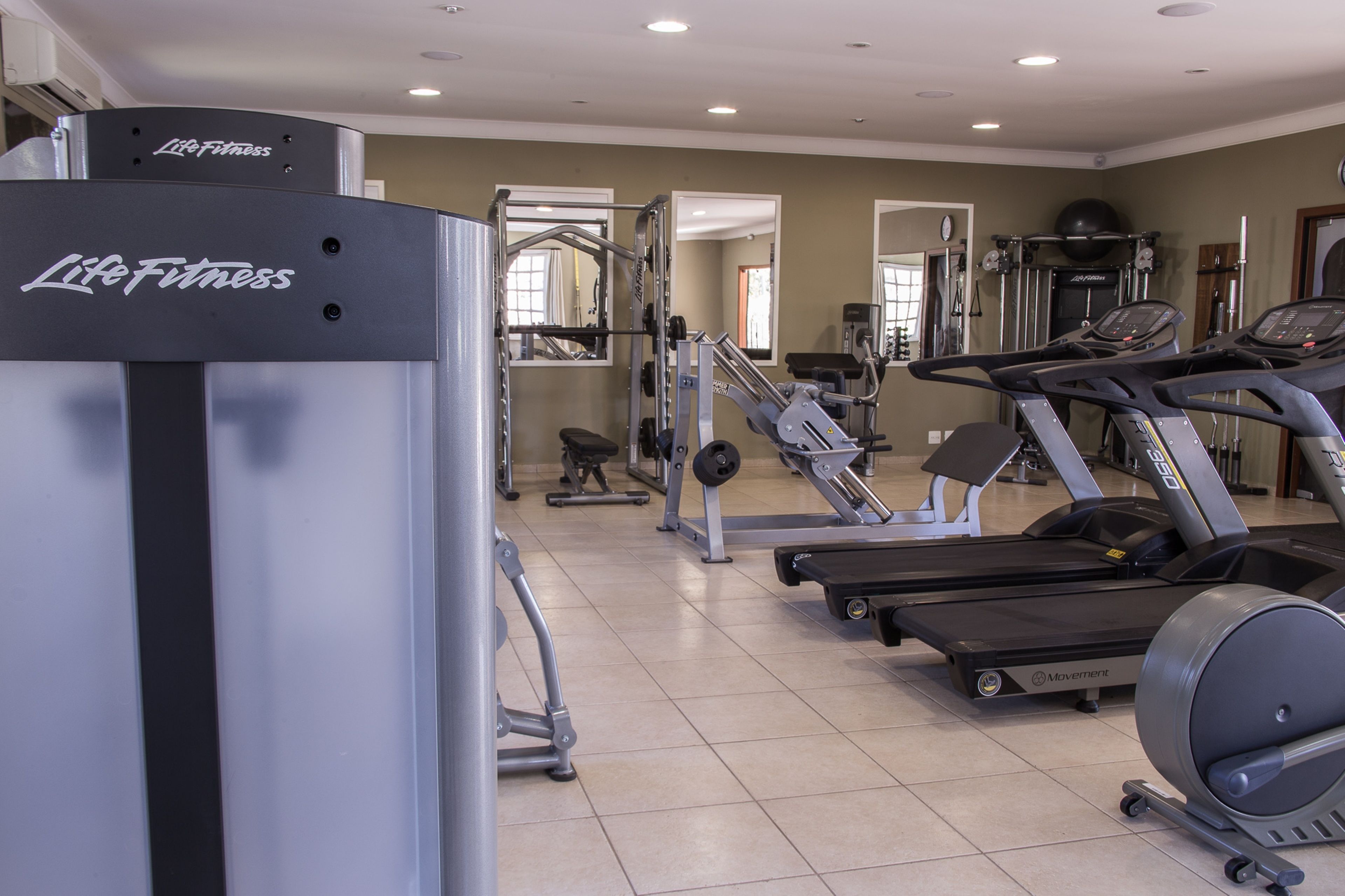 A gym with treadmills, a weight machine, and a mirror.