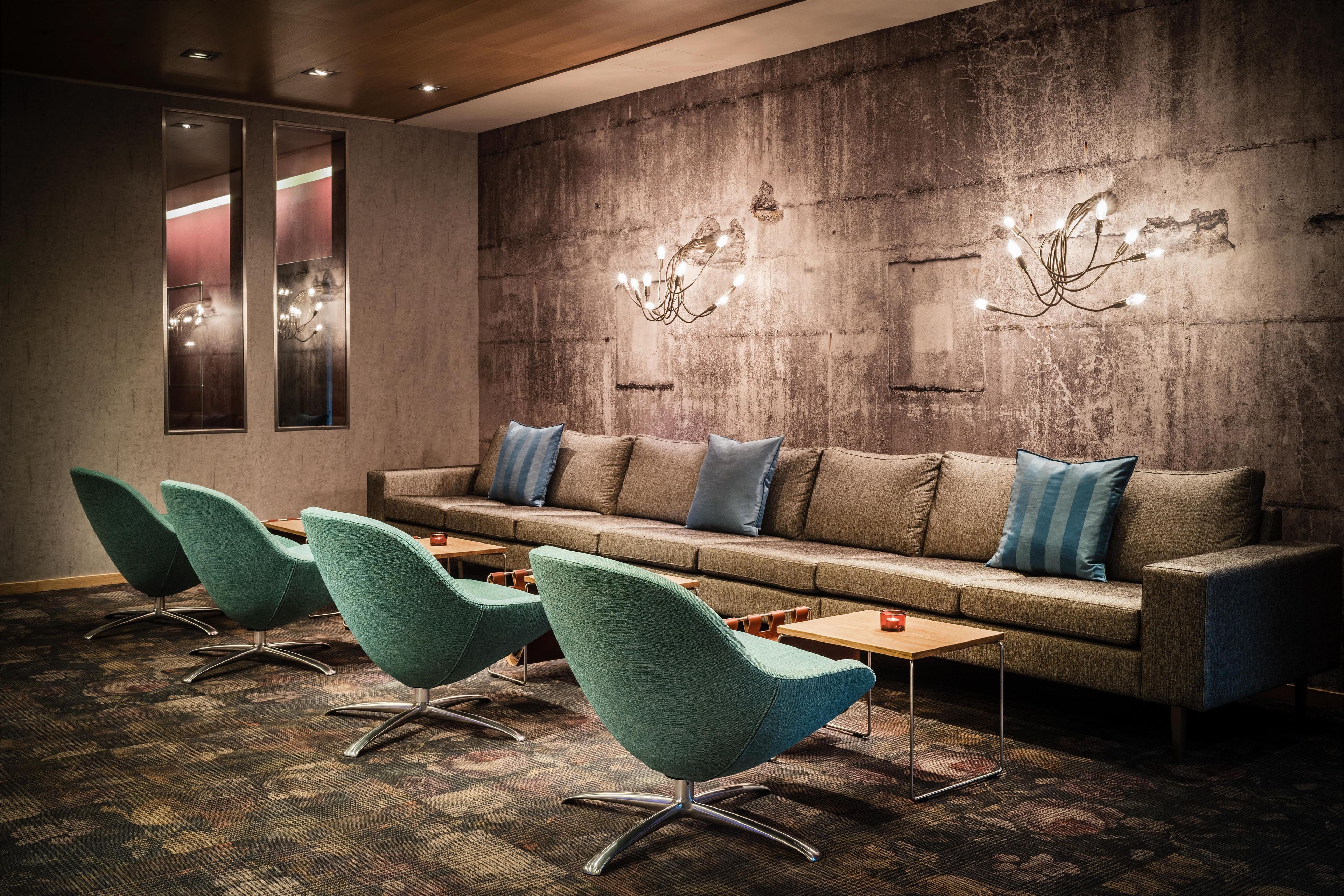 A lounge area with a sofa, chairs, and a patterned carpet.
