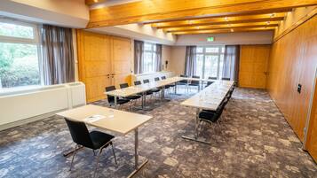 Une salle de conférence dotée de longues tables, de chaises et offrant une vue sur l’extérieur grâce à de grandes fenêtres.