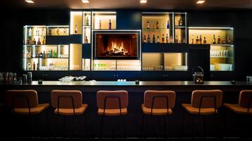 Eine Bar mit mehreren Regalen voller Spirituosenflaschen, Gläsern und einem Kamin.