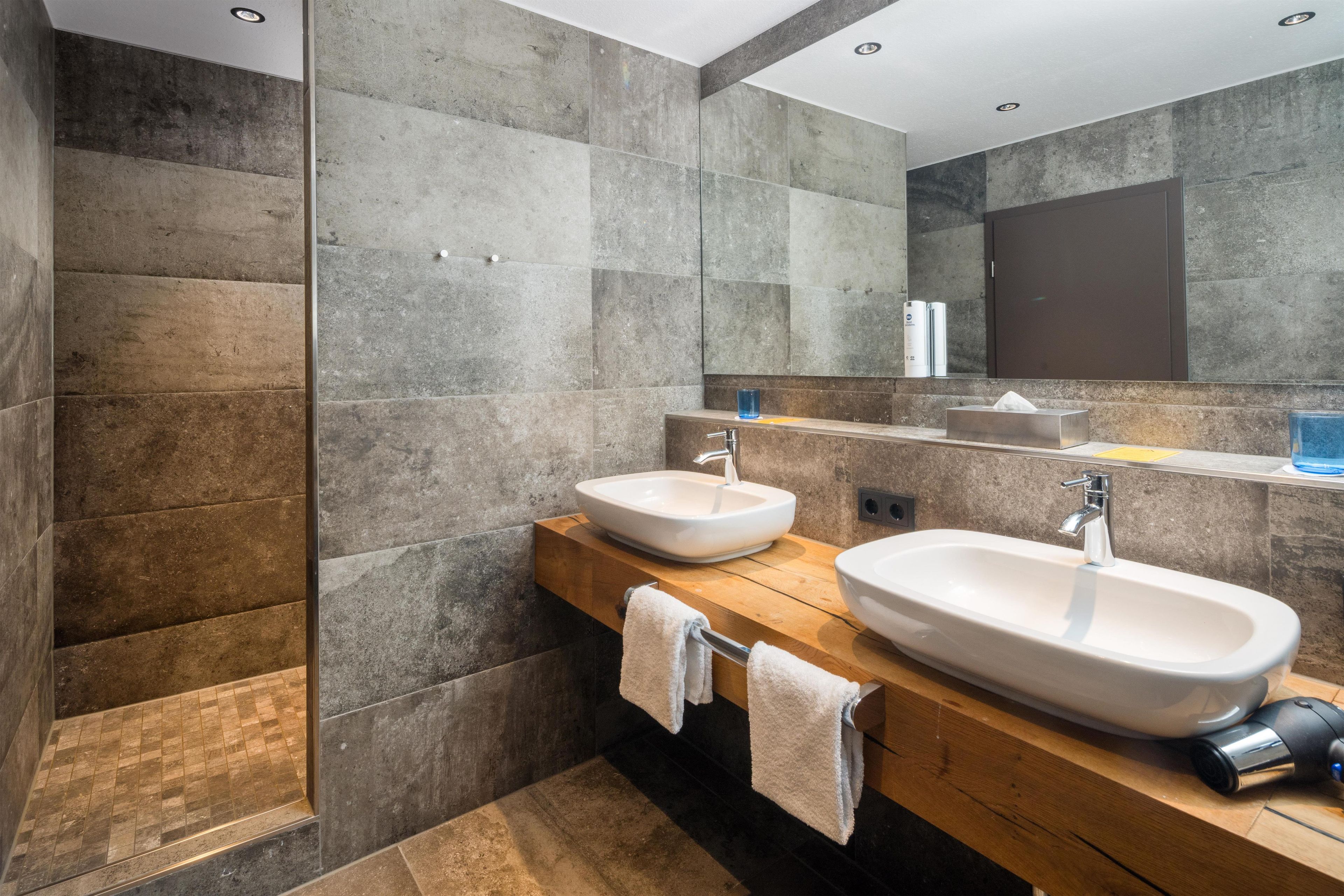 Une salle de bain moderne avec deux lavabos, un miroir et un espace douche.
