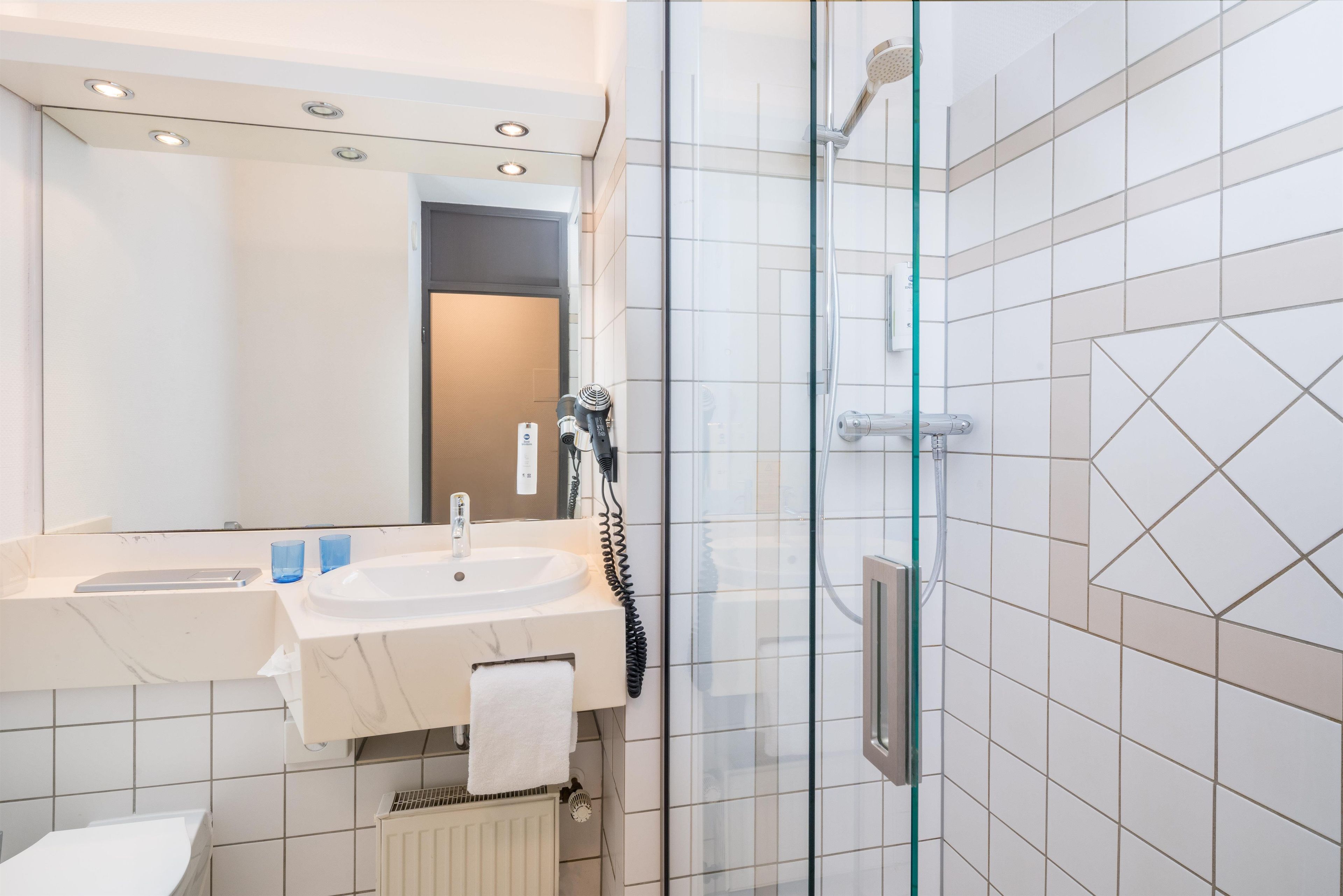 A modern bathroom with a glass shower enclosure, a sink with a towel, and a mirror above the sink.