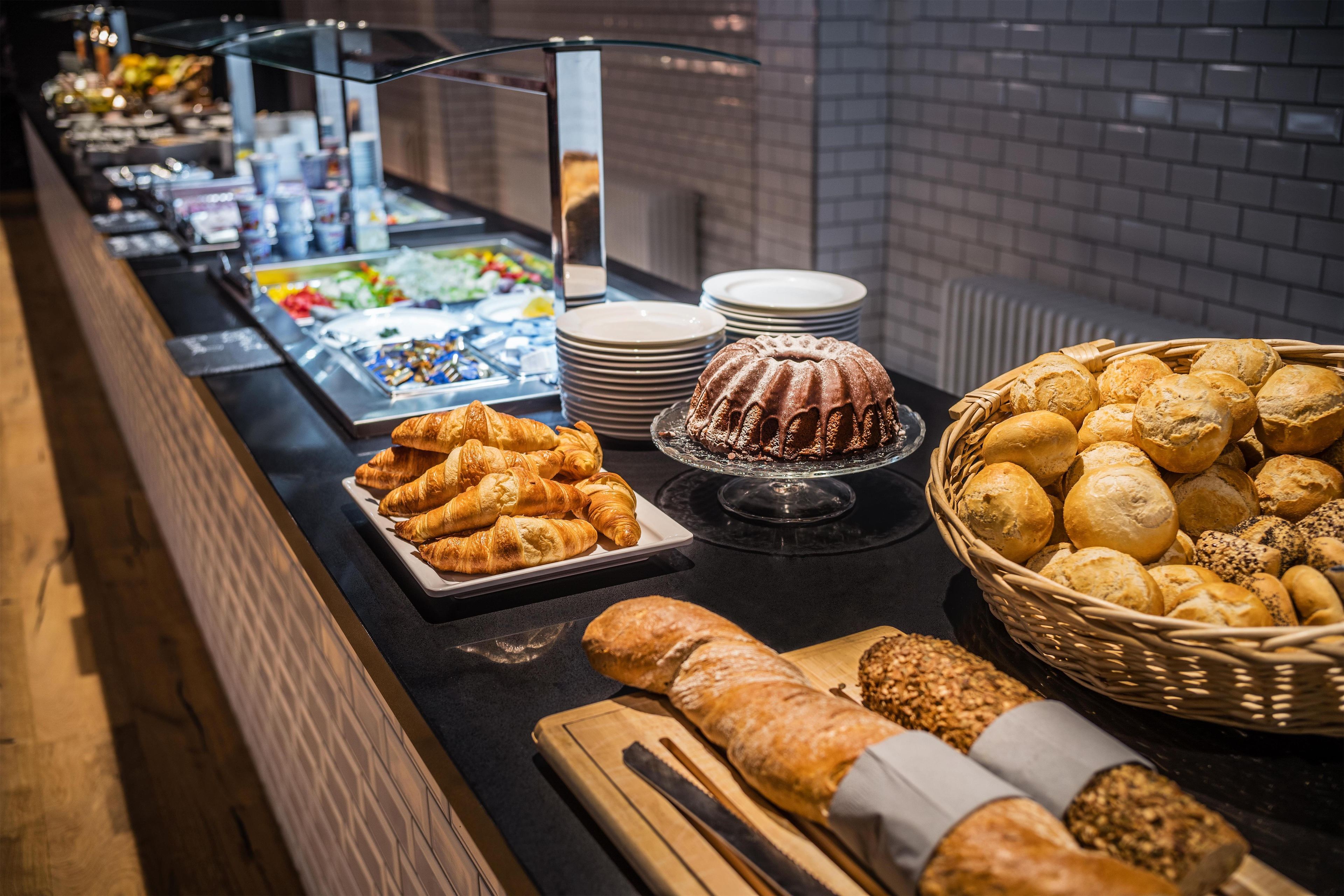 En buffet med forskellige bagværk, heriblandt brød, kager og en bundtkage.