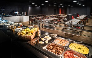Guests can enjoy a wide selection of food at the buffet, featuring fresh fruits, eggs, sausages, and more.