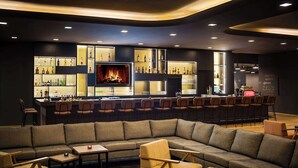 A modern bar area with a sofa and chairs, a bar counter with bottles, and a fireplace. - Best Western Hotel Kaiserslautern (Kaiserslautern)