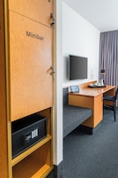 Un minibar con un televisor, escritorio, silla y un control remoto en el suelo.