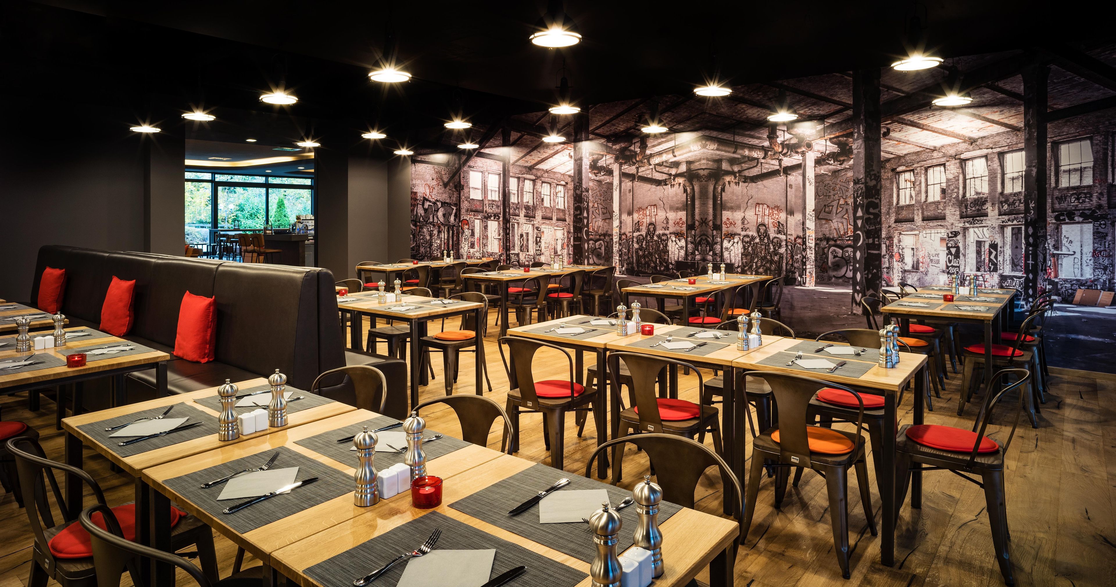 Ein Restaurant mit mehreren Tischen, Sitzecken und einer hohen Decke mit freiliegenden Holzbalken.