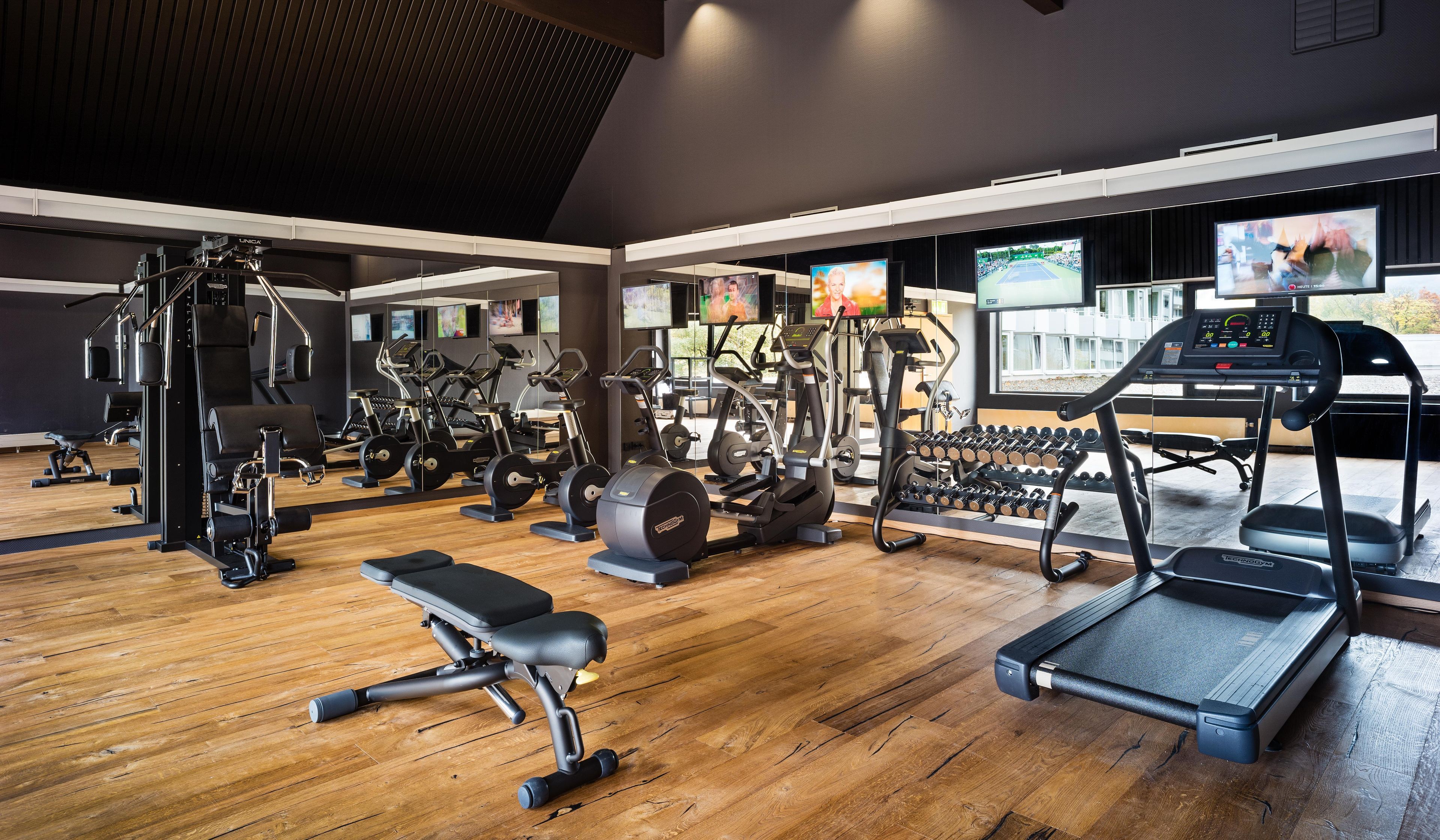 A gym with various exercise equipment, including treadmills, weight machines, and free weights.