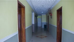 A hallway with a patterned ceiling, wooden doors, and a tiled floor. - De Prince Guest House (Lagos)