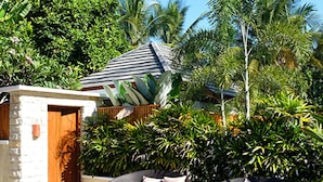 A tropical outdoor seating area with wicker chairs and a small stone structure. - Villa Bau Nyale (Kuta)