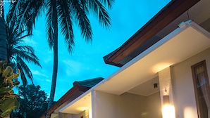 A modern house with a covered porch, large potted plants, and a pathway leading to the entrance. - Villa Bau Nyale (Kuta)