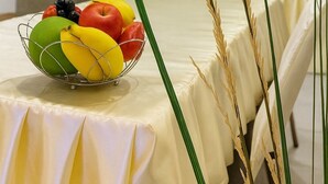Een eethoek met een tafel gedekt voor twee personen, inclusief een fruitschaal en decoratieve planten.