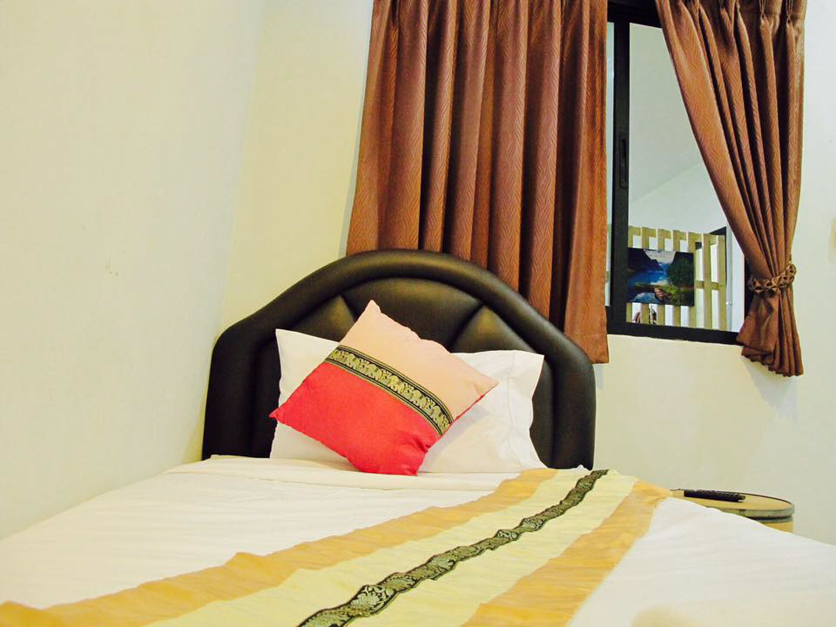 A bed with a black headboard, a white and red pillow, and a striped bedspread.