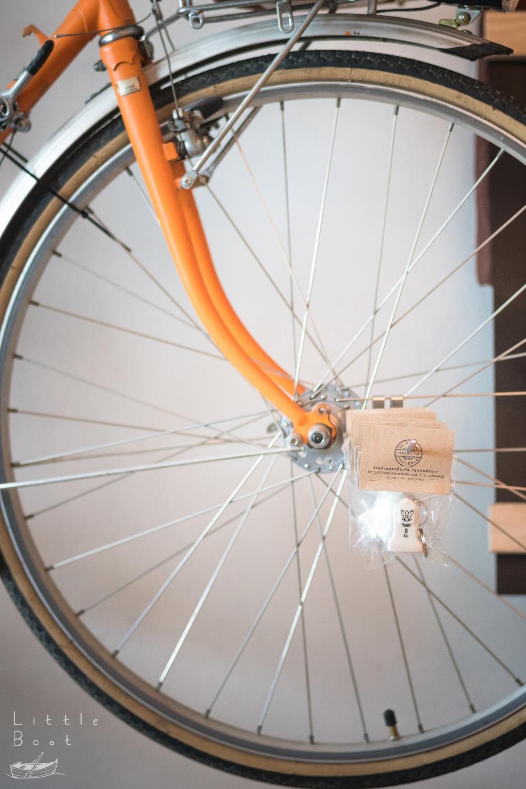 A bicycle wheel with an orange frame and a small package attached to the hub.
